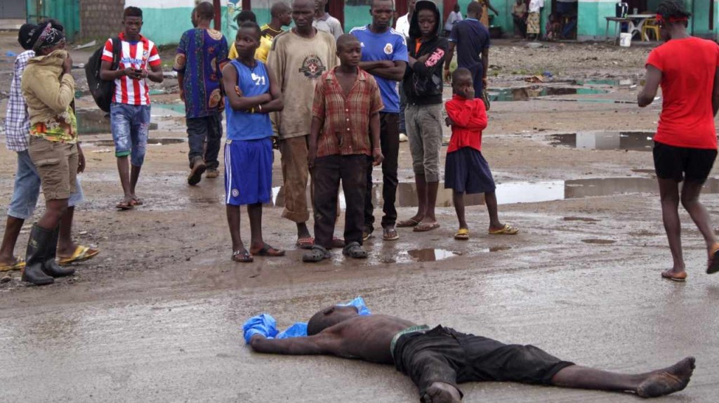 EBOLA. La gente se reúne en torno a un hombre muerto por el virus del Ébola, en una de las principales calles de las afueras de centro de la ciudad de Monrovia, Liberia. 